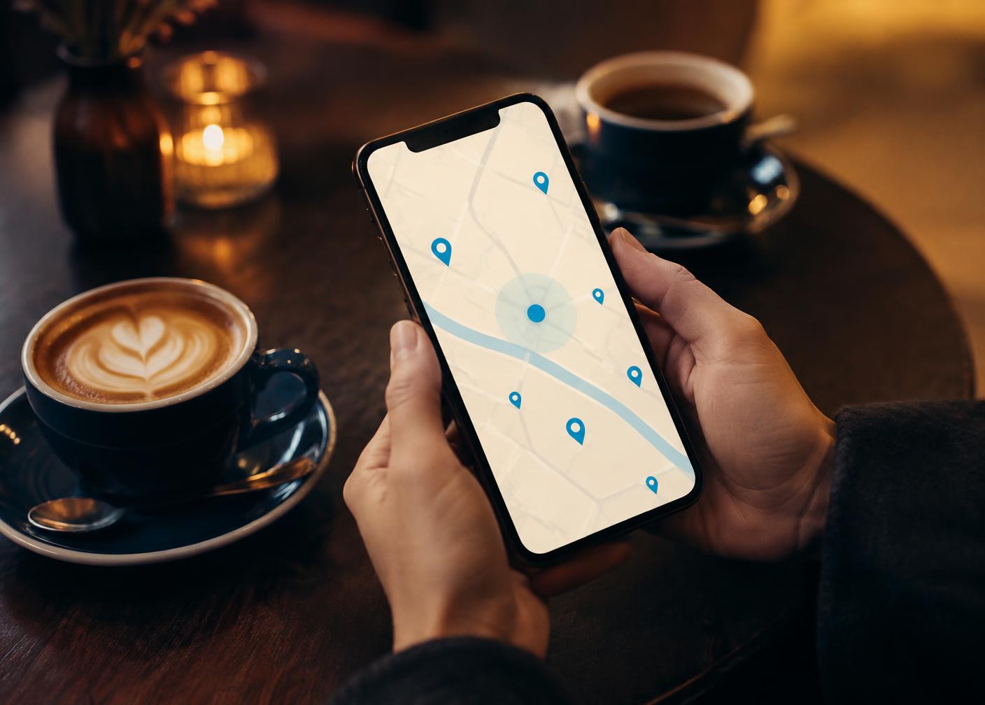 Illustrative image: a smartphone showing a map with venue pins in a café